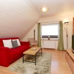 Ein Wohnzimmer mit rotem Sofa, Holztisch und Fernseher.
