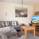 Wohnzimmer mit Sofa, Couchtisch und Fernseher. Wandbild und Kamin sichtbar.