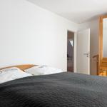 Schlafzimmer mit Bett, Kleiderschrank und Tür zum Bad.