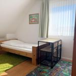 Ein Schlafzimmer mit einem Bett, einem Schreibtisch und einem Fenster mit Vorhängen.
