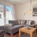 Wohnzimmer mit Sofa, Tisch und Fenster zur Terrasse.