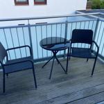 Terrace with two chairs and a round glass table.