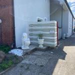 House with white lion sculptures and wooden fence. Plant in pot. Pavement and stone slabs.