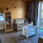 Living room with sofa, coffee table, and bookcase. Balcony with seating.