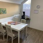 Dining room with white table, four chairs, and kitchenette with microwave and coffee maker.