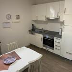 Kitchen with white cabinets, stove, and dining table with chairs.