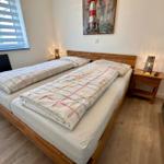 Schlafzimmer mit Doppelbett, Nachttisch und Fenster mit Jalousie.