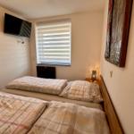 Schlafzimmer mit Doppelbett, Fenster, TV und Nachttisch mit Lampe.