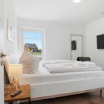 Schlafzimmer mit Bett, Fernseher und Fenster zum Garten