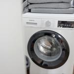 Waschmaschine mit Stapel grauer Wäsche darauf