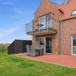 Roter Ziegelbau mit Balkon und Terrasse mit Gartenmöbeln und grünem Rasen.