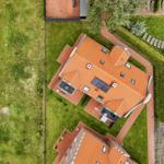 Haus mit orangefarbenem Dach und Gartenbereich mit Sonnenkollektoren.