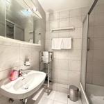 Badezimmer mit Waschbecken, Spiegel, Dusche und Handtüchern.