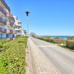 Pflasterweg entlang moderner Wohnhäuser mit Blick auf das Meer.