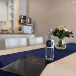 Tisch mit Blumen, Wasserflasche und Broschüre im Essbereich.