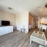 Wohnung mit Wohn- und Essbereich, Küche und Schlafzimmer. Holzfußboden und weiße Möbel.