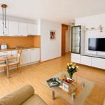 Living kitchen with dining area, glass table, sofa, and TV.