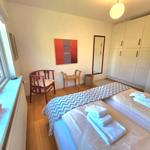 Zimmer mit zwei Betten, Schrank, Stuhl und Fenster. Handtücher ordentlich aufgebettet.