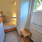 Zimmer mit Doppelbett, Etagenbett und Fenster mit Jalousie.