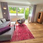 Wohnzimmer mit Sofa, Sessel, Teppich und Blick auf Garten