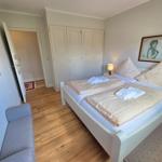 Schlafzimmer mit Doppelbett, Kleiderschrank und Sitzgelegenheit.