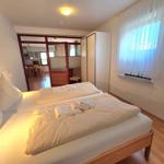 Bedroom with double bed, window, and view into the kitchen.