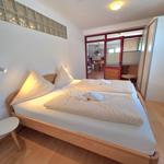 Bedroom with double bed, nightstand, and view into the kitchen.