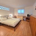 Bedroom with double bed, wooden floor, window, and wardrobe.