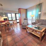 Living and dining area with sofa, armchair, dining table, and kitchen.