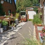 Backyard with terrace, plants, and garden furniture. Entrance door and mailbox on the wall.