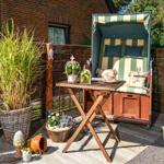 Garden with lounge chair, table, and plants.