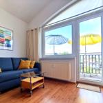 Lichtdurchfluteter Wohnbereich mit blauer Couch und Zugang zum Balkon