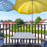 Sonniger Balkon mit Sitzmöbeln und gelbem Sonnenschirm im Sommer
