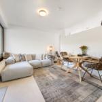Living and dining area with sofa, table and chairs. Glass door leads to balcony.