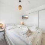 Bedroom with white bed, nightstand, lamp, and closet.