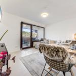 Living and dining area with table, chairs, and view of balcony.