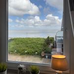 View from the window to beach and sea under blue sky with white clouds.