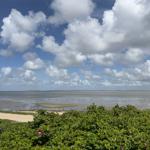 Wide beach with tidal flats and blue sky with white clouds.