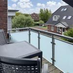 Balcony with table and chairs, view of houses and trees.