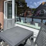 Terrace with gray table and chairs, glass railing, and view of rooftops.