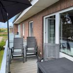 Terrace with table, three chairs, and umbrella. View of garden and neighboring houses.