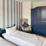 Room with two beds, blue wardrobe, and striped wall wallpaper.