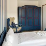 Bedroom with bed, chair, and wardrobe. Wall with stripe pattern.