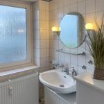 Bathroom with sink, mirror, and window with frosted glass.