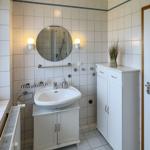 Bathroom with sink, mirror, shower, and cabinets.
