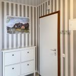 Room with striped wall, white door, and cabinet with picture.