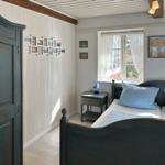 Schlafzimmer mit Doppelbett, drei Fenstern und Wandbildern.