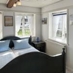 Schlafzimmer mit Bett, Kleiderschrank und Blick in die Küche.