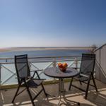 Terrace with two chairs and table. View into living room with TV and dining table.