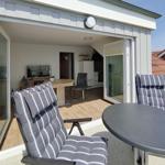 Terrace with table and chairs. In background, living room with dining table and TV.